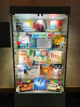Library Exhibit Case with glass shelves, lighting, and colorful books.