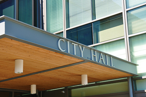 Entrance of a modern building with a wooden canopy and the words 