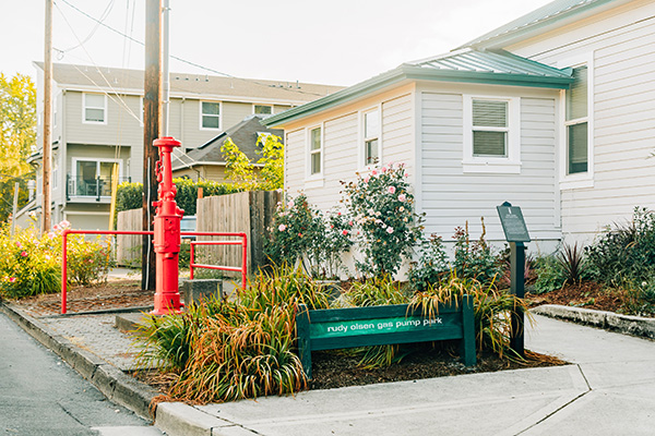 Small urban park with a red gas pump and a green sign reading 