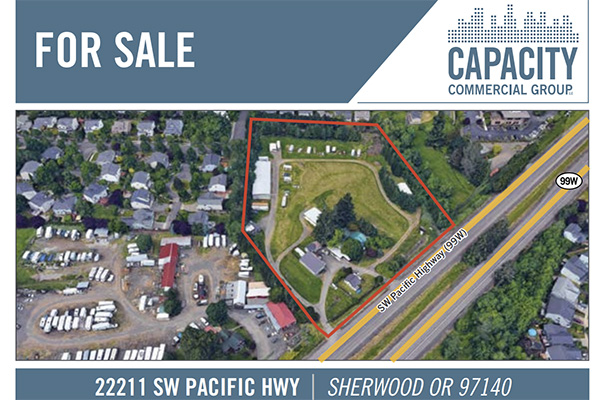 Aerial view of a property for sale outlined in red, located at 22211 SW Pacific Hwy, Sherwood, OR 97140. Surrounding area includes homes and a highway.