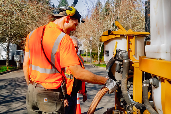 Construction workers adjusting a tube on a machine.