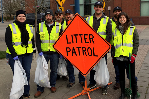 A group of people in high-visibility vests standing behind an orange 