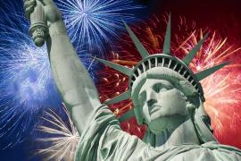 The Statue of Liberty with colorful fireworks in the night sky behind it.
