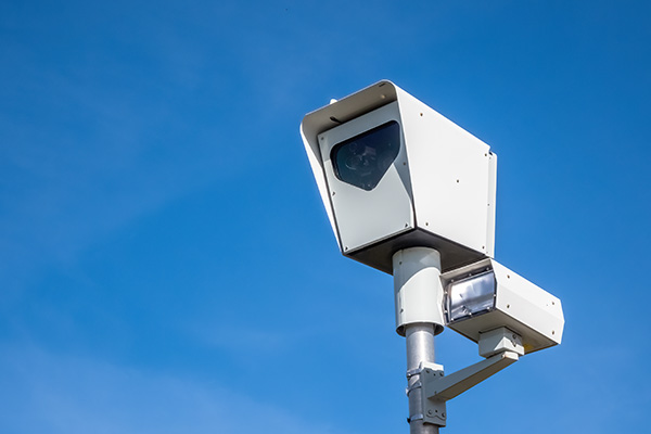 A close up to a traffic speed Camera or red light camera on a sunny day with a blue sky.