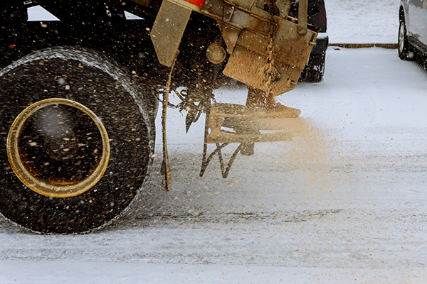 A maintenance truck salts the road during snow