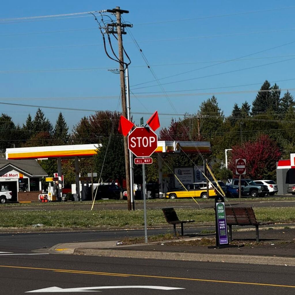 A stop sign with bent red flags stands at the four-way stop intersection near Chick-fil-A.