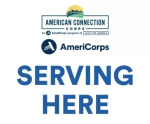 Sign displaying “American Connection Corps AmeriCorps Serving Here” with AmeriCorps and Lead for America logos.