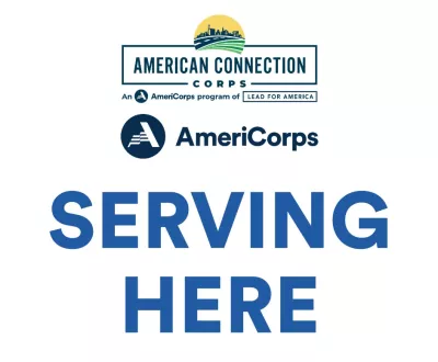 Sign displaying “American Connection Corps AmeriCorps Serving Here” with AmeriCorps and Lead for America logos.