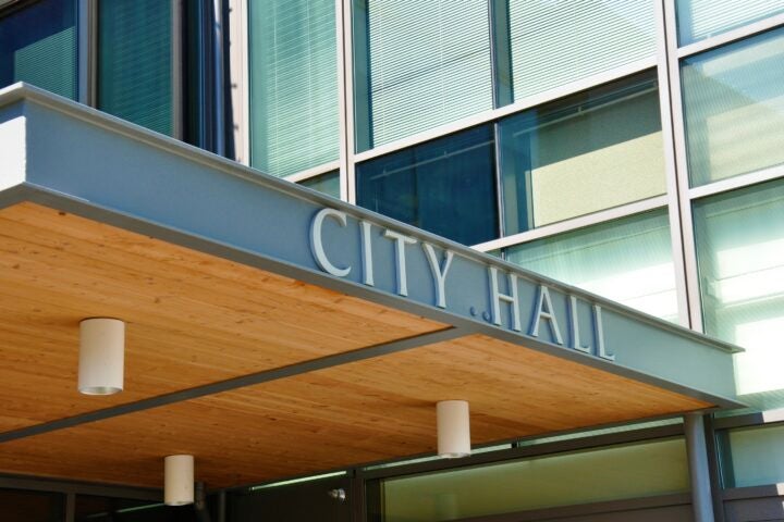 Modern city hall entrance with large windows and a sign reading 