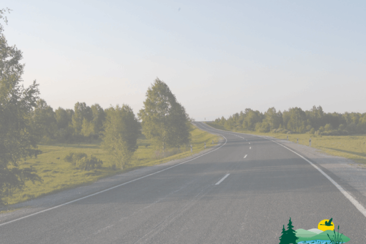 A paved road curves through a grassy, tree-lined landscape under a clear sky, with the City of Sherwood, Oregon logo in the lower right corner.