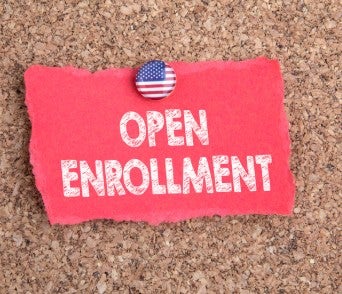 Red paper pinned to a corkboard with the words “OPEN ENROLLMENT” written in white.